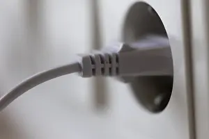 Energy Efficiency Concept Impressions: White power plug in a socket on the wall